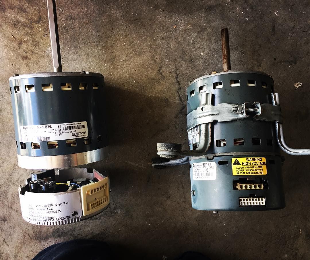 Failed blower motor beside its replacement, both ECM units, laid on the floor