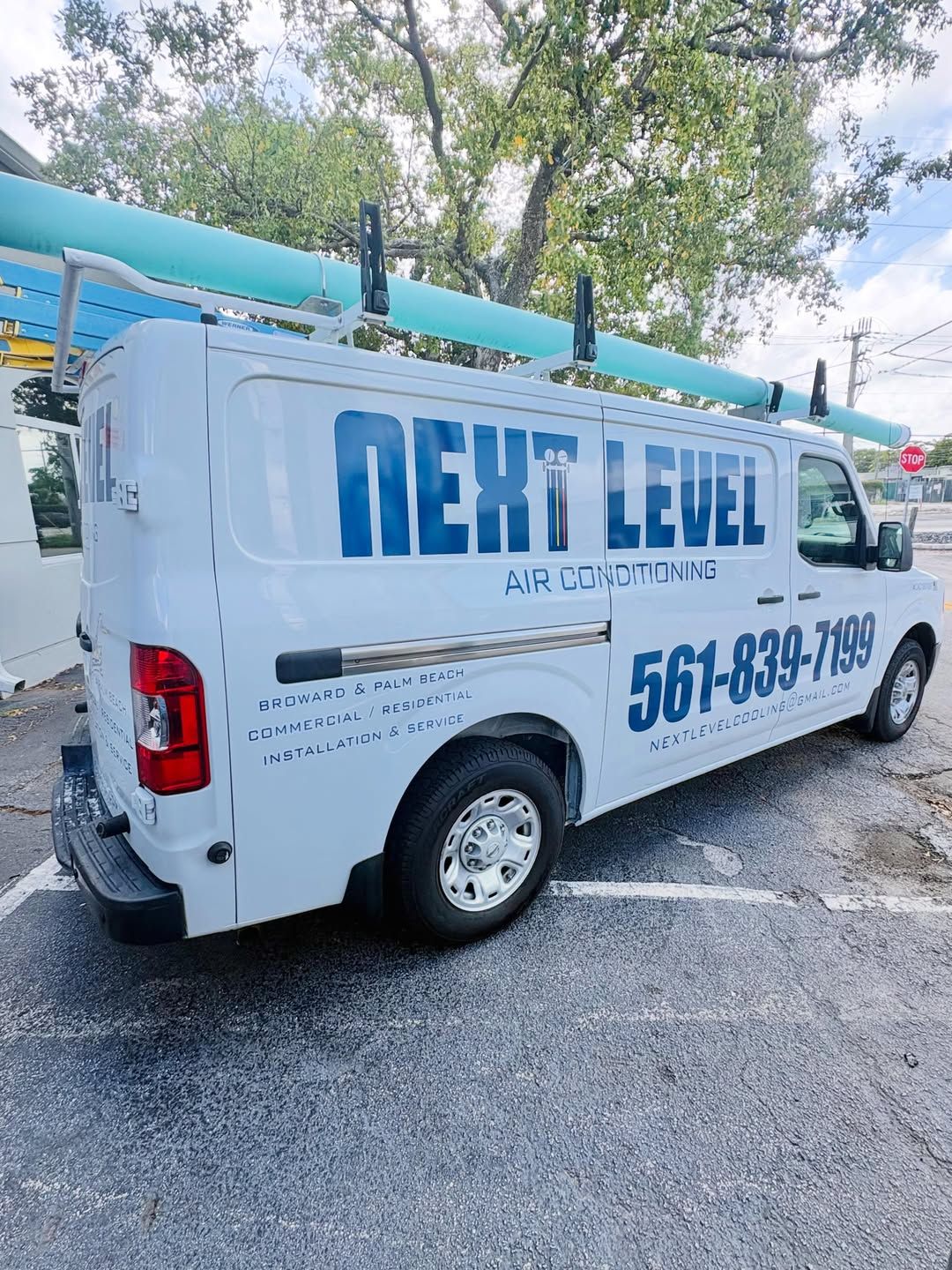 Branded service van, side view, ladder rack loaded, in a car park