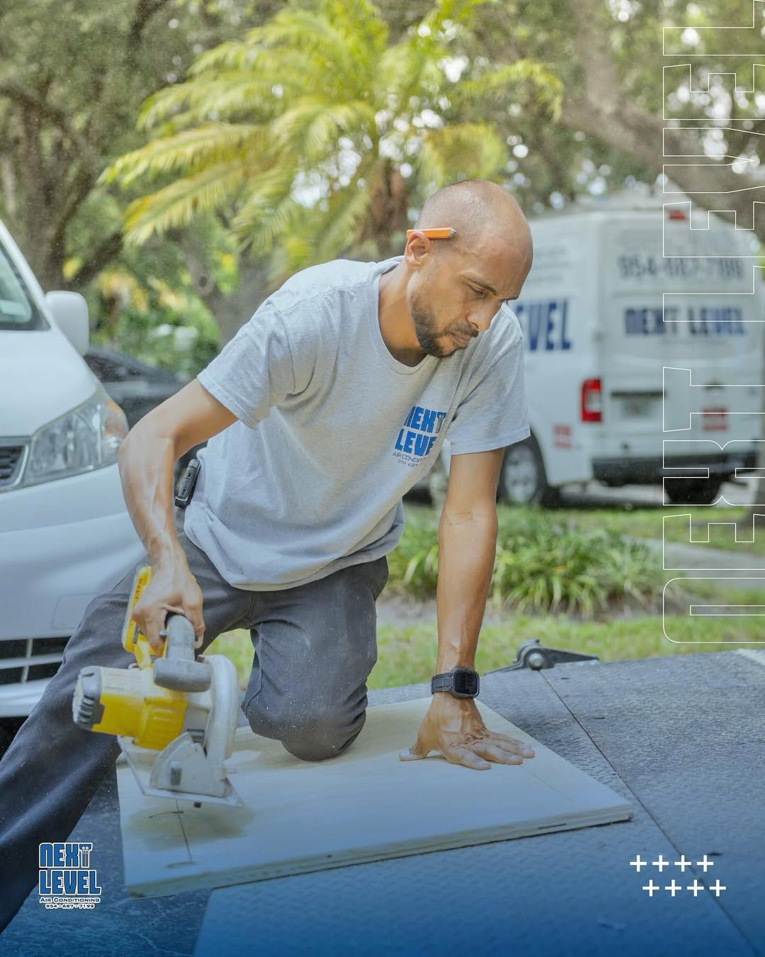 Technician cutting duct board on a truck bed with a branded van behind him