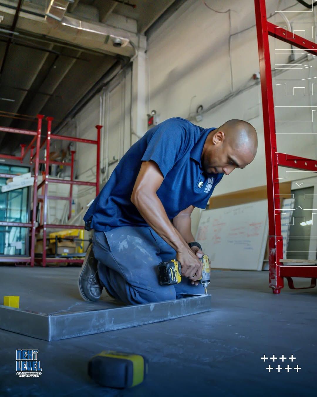 Technician kneeling in a warehouse driving screws into a sheet metal base